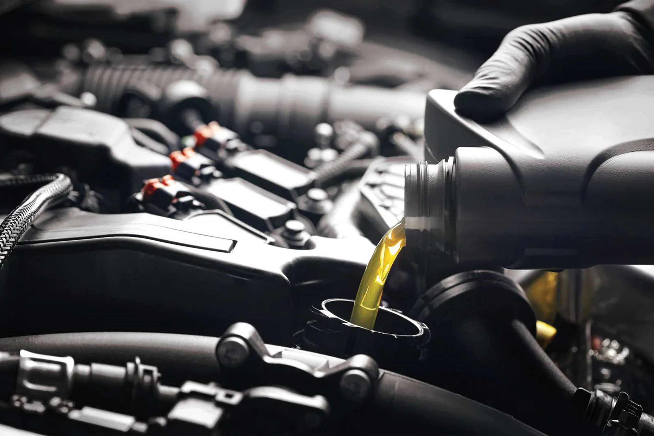 Car painter in protective clothes and mask painting automobile bumper with metallic paint and varnish in chamber workshop.