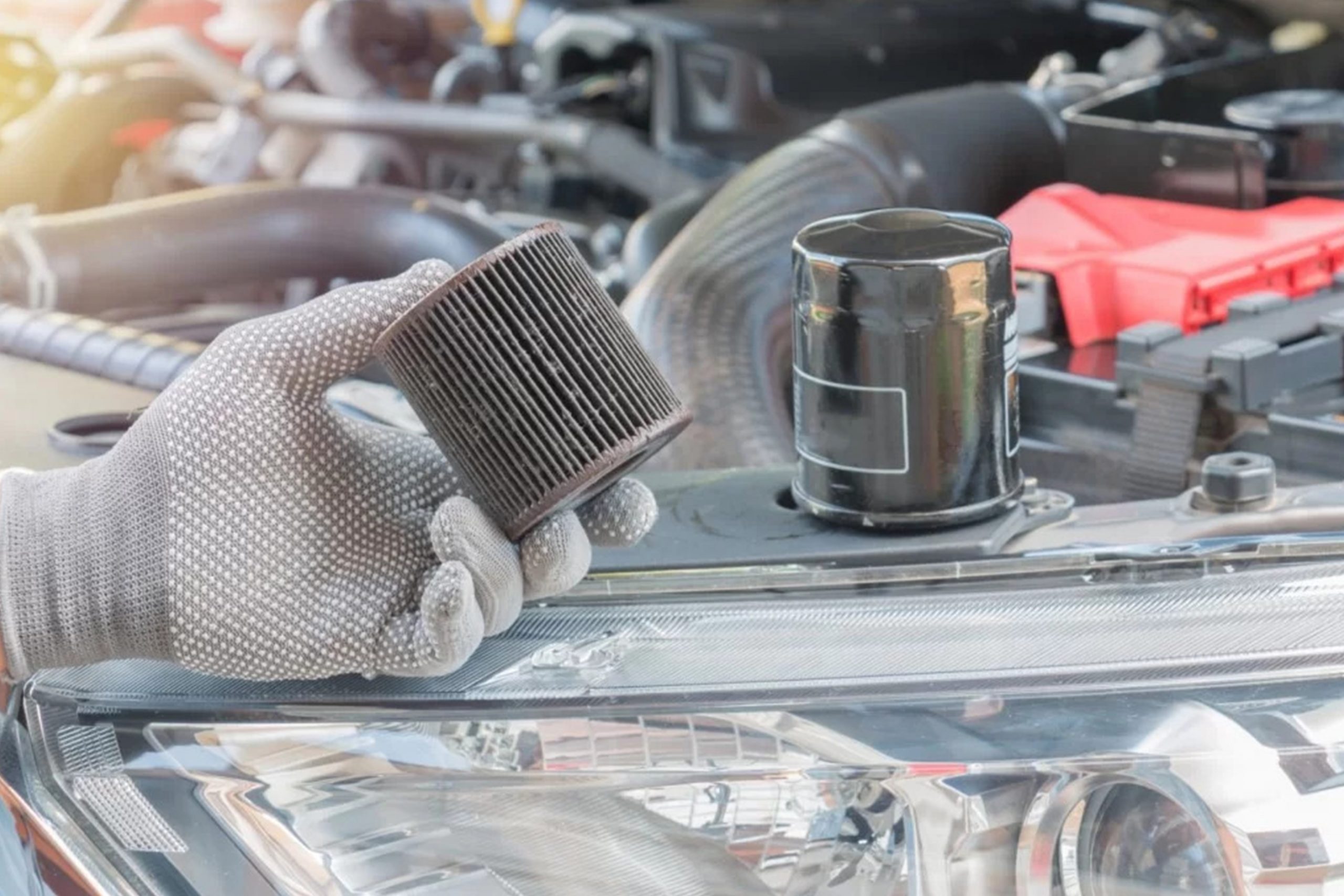 Car painter in protective clothes and mask painting automobile bumper with metallic paint and varnish in chamber workshop.