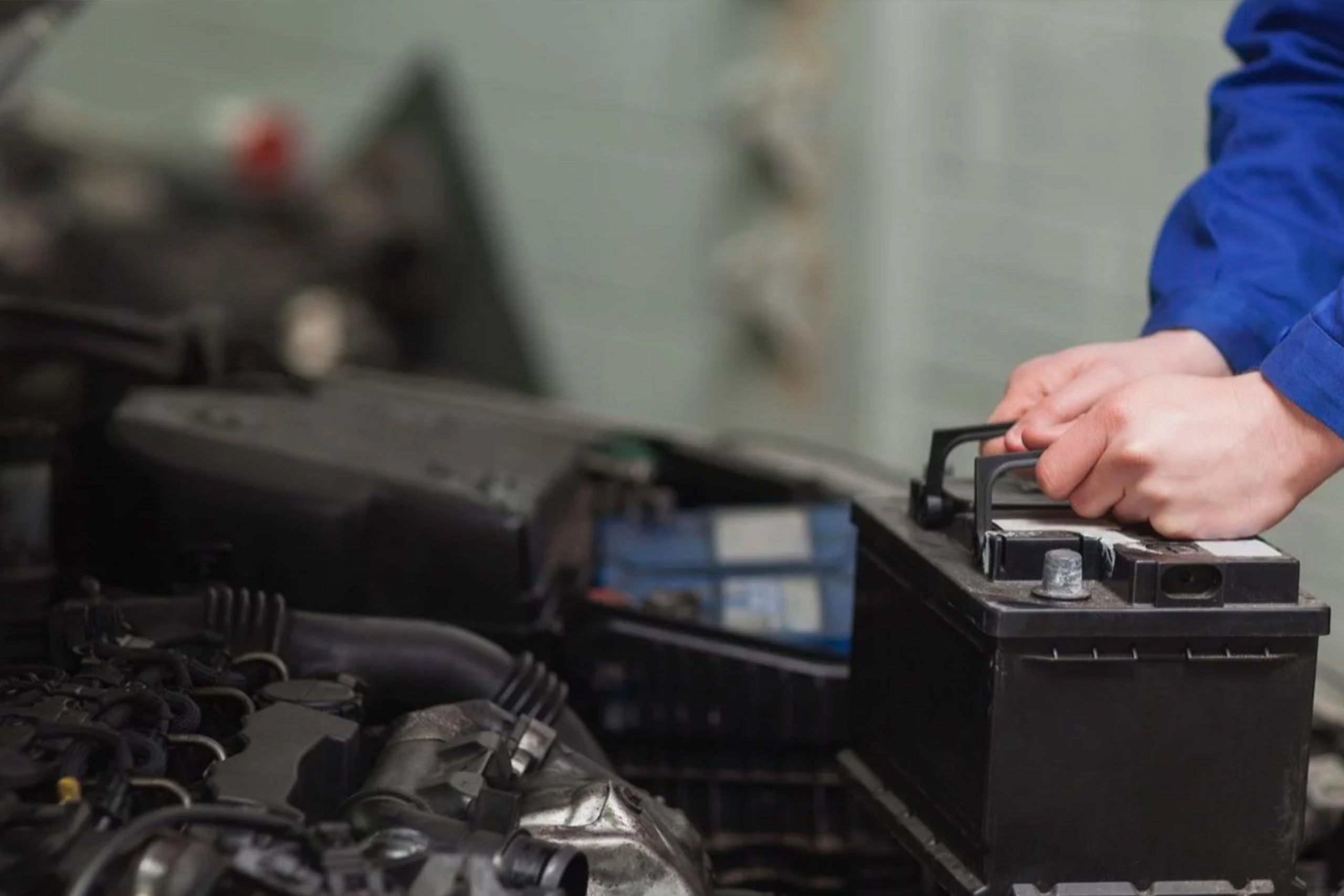 Car painter in protective clothes and mask painting automobile bumper with metallic paint and varnish in chamber workshop.