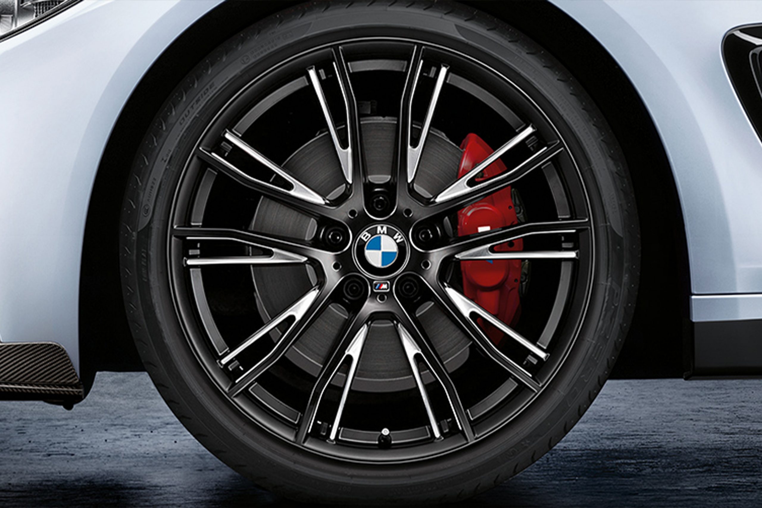 Car painter in protective clothes and mask painting automobile bumper with metallic paint and varnish in chamber workshop.