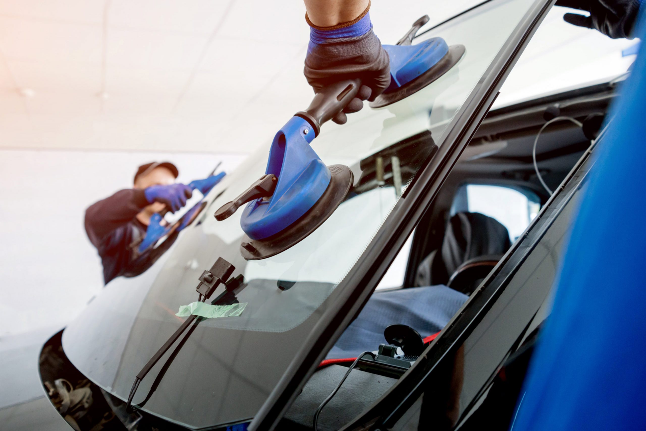 Car painter in protective clothes and mask painting automobile bumper with metallic paint and varnish in chamber workshop.